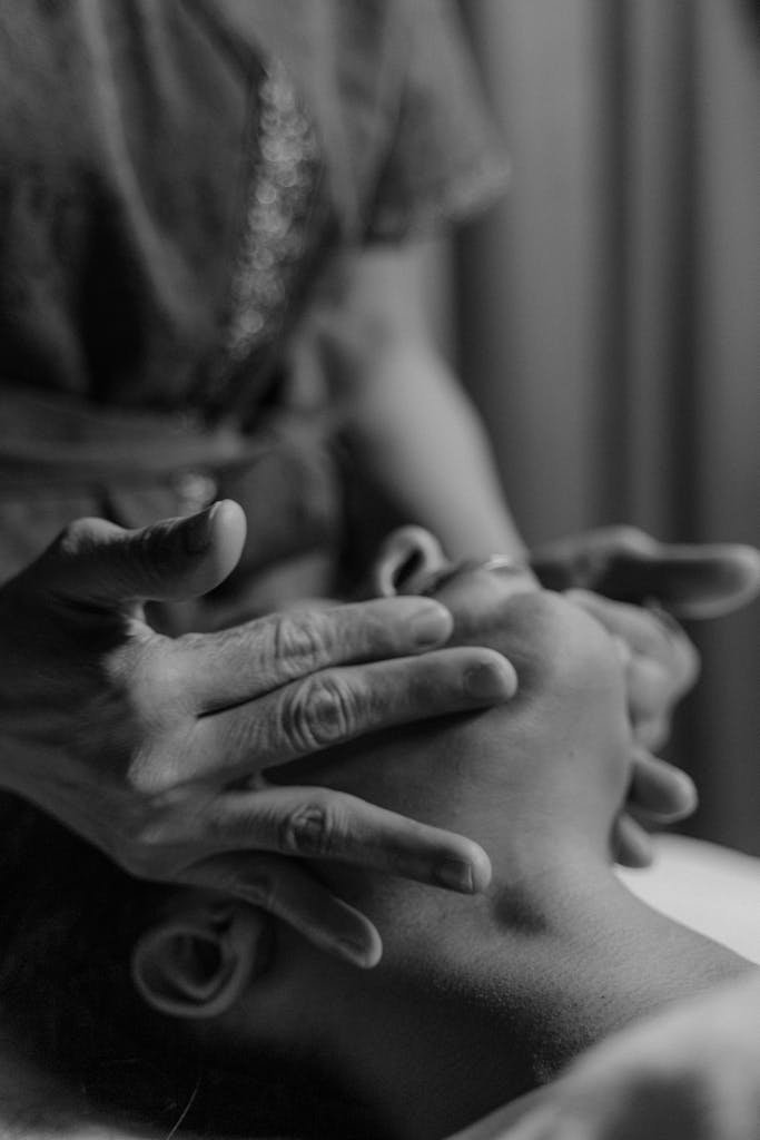 A serene black and white image of a woman receiving a relaxing facial massage.
